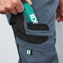 Lade das Bild in den Galerie-Viewer, Detail view of Workwear Trousers featuring two cargo side pockets with flaps and two back pockets with Velcro fastening.